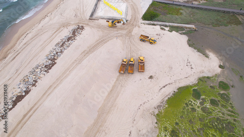 Esposende, Portugal, April 10, 2022: Aerial view of the two sides of Restinga de Ofir. Esposende fishing harbor maintenance dredging. Dumper vehicles and rotating excavator parked on the sand. photo
