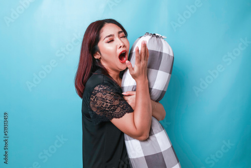 Fotografi Portrait of sleepy attractive Asian woman wearing pajamas, holding bolster feeli