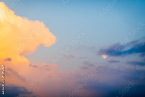 Picturesque sunset sky with bright clouds and moon