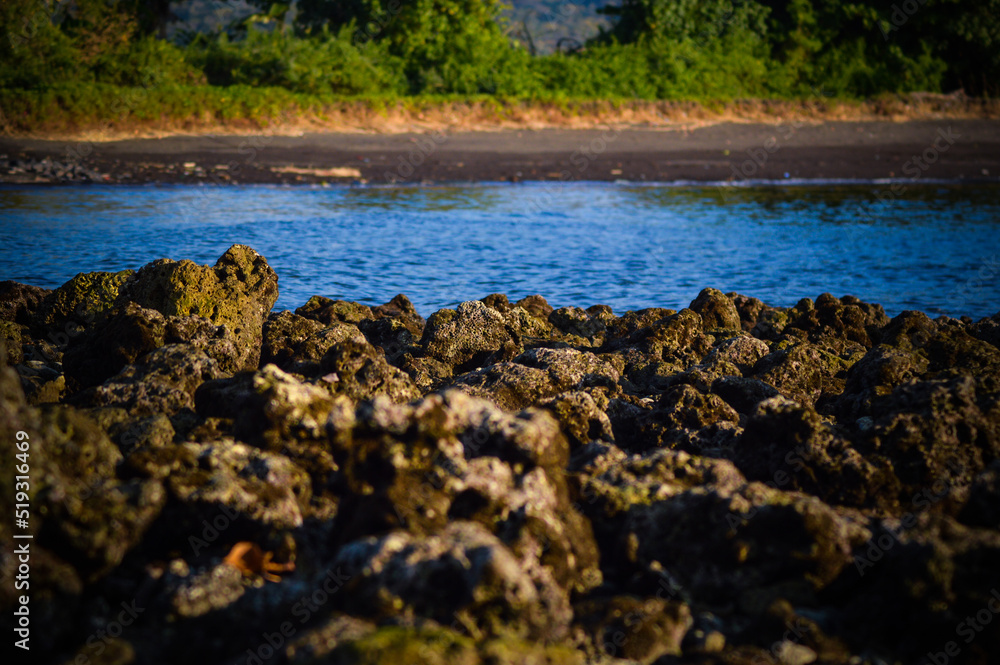 Natural Scenic View Chunks Of Rocks And Calm Sea Water Waves On Tropical Beach Village In The Afternoon Natural Scenic View Chunks Of Rocks And Calm Sea Water Waves On Tropical Beach Village In The Afternoon