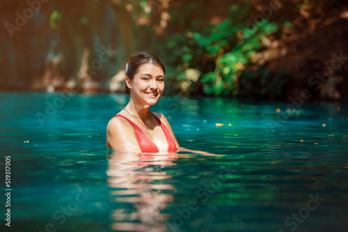 young Latina woman standing in blue green waters of Rio Blanco in Costa Rica