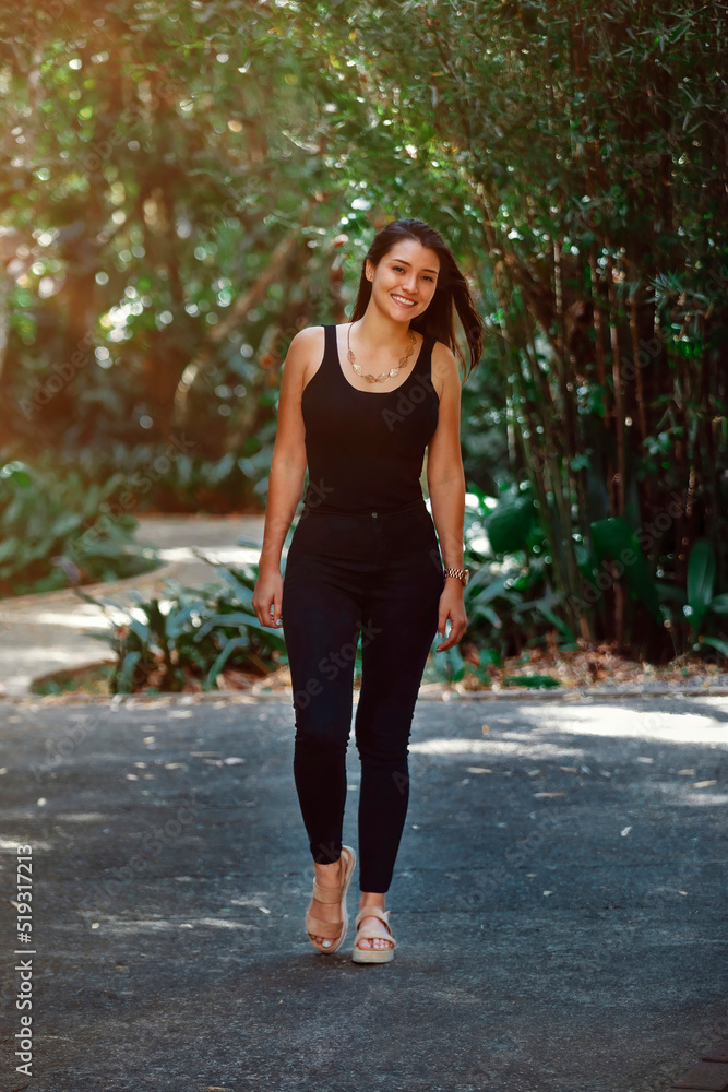 young Latina woman dressed in black jeans and tank top walking in a park in Costa Rica