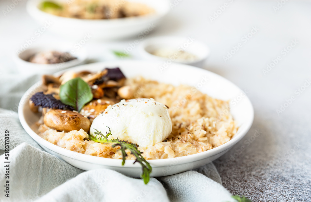 Savory porridge for breakfast. Oatmeal or spelt flakes with poached egg, fried mushrooms, herbs. Healthy food. Keto diet. Savory porridge for breakfast. Oatmeal or spelt flakes with poached egg, fried mushrooms, herbs. Healthy food. Keto diet.