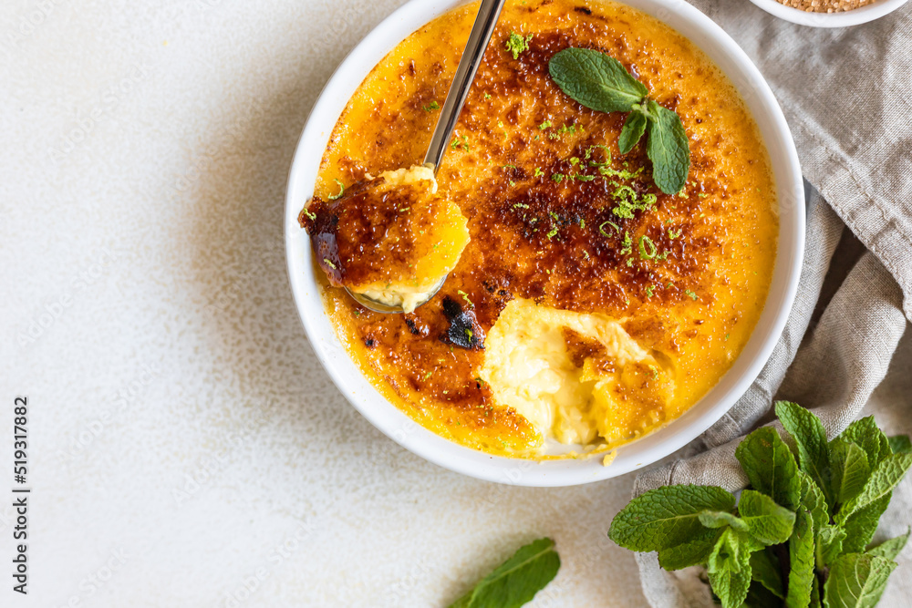 Creme brulee with caramel crust and mint in ceramic dishes. Famous french dessert. Delicious desserts for cafe or restaurant. Top view. Creme brulee with caramel crust and mint in ceramic dishes. Famous french dessert. Delicious desserts for cafe or restaurant. Top view.