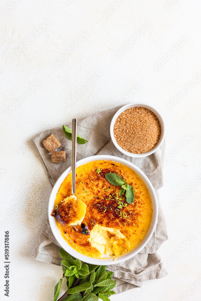 Creme brulee with caramel crust and mint in ceramic dishes. Famous french dessert. Delicious desserts for cafe or restaurant. Top view. Creme brulee with caramel crust and mint in ceramic dishes. Famous french dessert. Delicious desserts for cafe or restaurant. Top view.
