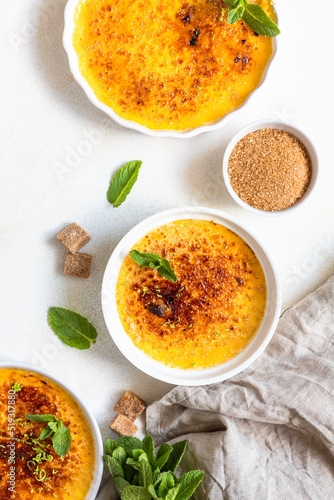 Creme brulee with caramel crust and mint in ceramic dishes. Famous french dessert. Delicious desserts for cafe or restaurant. Top view.