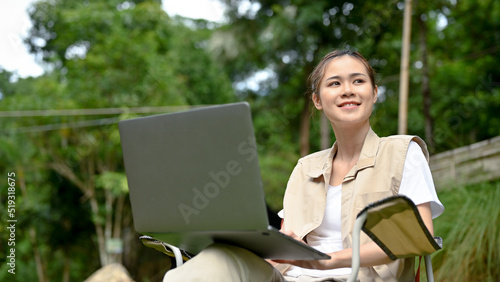 Fényképezés Beautiful young Asian female using laptop while looking at the beautiful view of nature forest