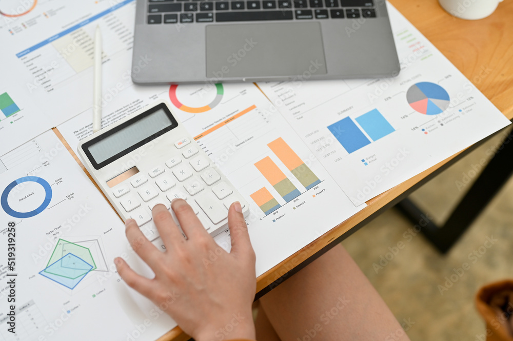 Top view, A female accountant or financial worker working at her office desk, using calculator and analysing financial tax data on the report. Top view, A female accountant or financial worker working at her office desk, using calculator and analysing financial tax data on the report.
