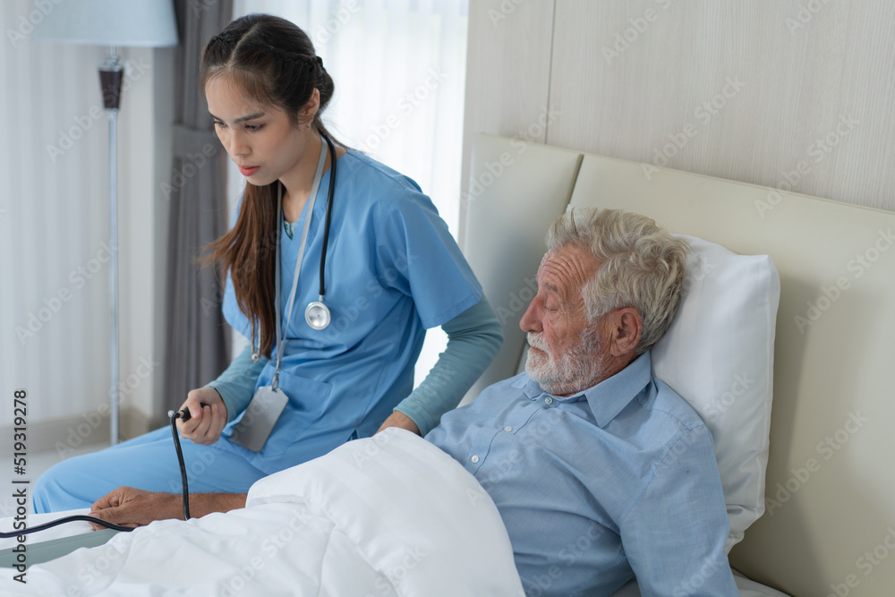 Fototapeta premium Asian nurse caregiver examining senior patient using blood pressure gauge. Female therapist take care of grandfather on bed in nursing home. healthcare and medical insurance
