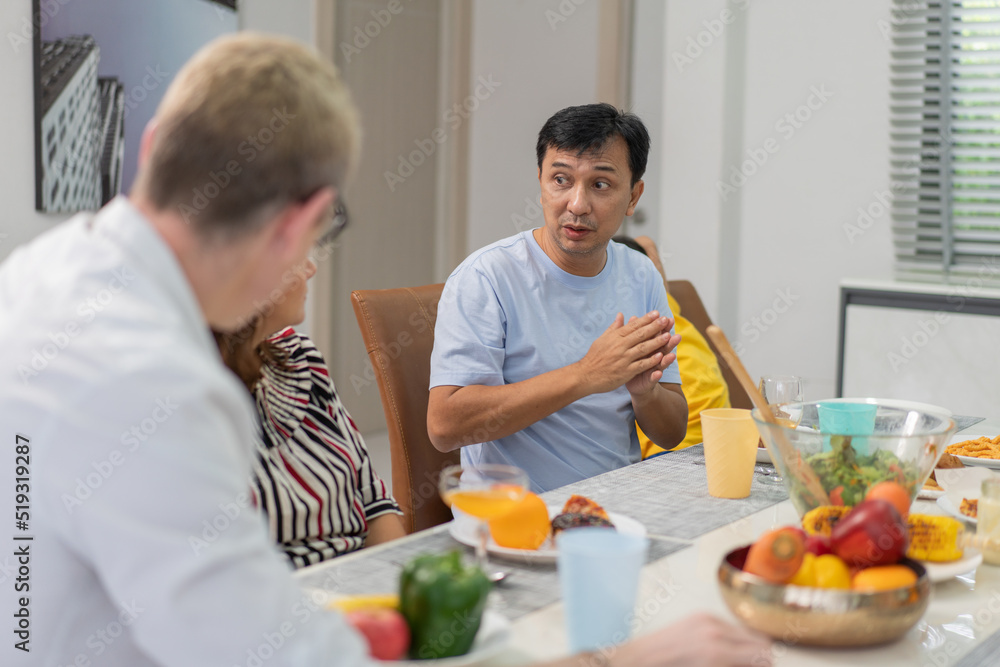Diverse family meeting and having dinner together sitting at the table at home. Caucasian couple visiting relatives. people enjoy talking while eating food.