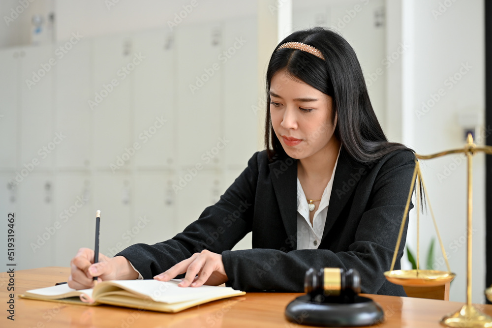 Confident Asian female lawyer making a resignation letter and working at her office desk. Confident Asian female lawyer making a resignation letter and working at her office desk.