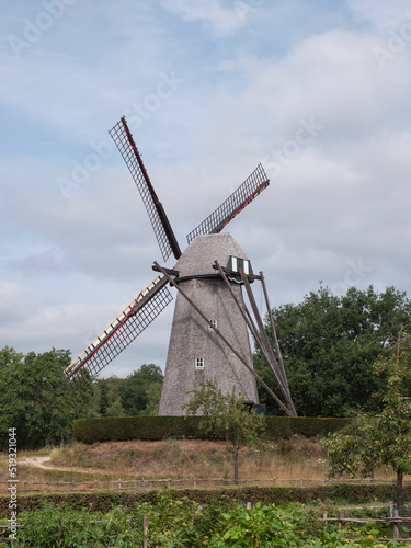 Landscape photo of an old windmill in Bokrijk, Belgium with a slightly cloudy sky