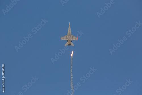 Warfare concept image. Modern jet fighter doing manuevers on a sunny day. Looks like missile is hitting on a jet fighter. photo