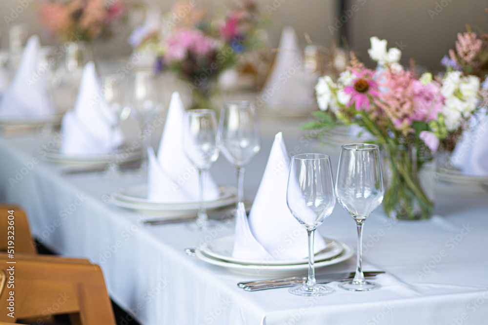 Fototapeta premium An example of setting tables for a wedding. Wedding decorations. Setting the table for the celebration. Flowers on the table. Preparation for the wedding.