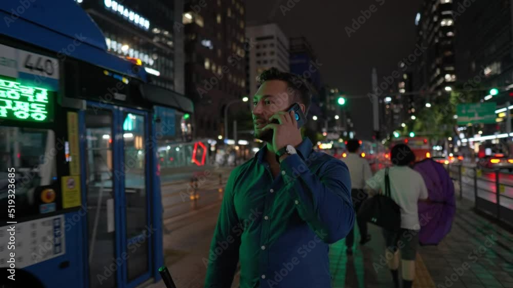 Bearded man talking on phone while waiting for public transportation at bus station at Night Downtown Gangnam station of Seoul Bearded man talking on phone while waiting for public transportation at bus station at Night Downtown Gangnam station of Seoul