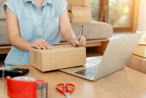 Close up online business owner prepares product for delivery to the customer. Online entrepreneur writing address on parcel box for delivery to customer. small business owner, SME concept.