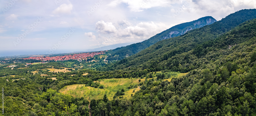 Mount Olympus, Greece. Small Greek village in the background. Forest hills and cloudy sky. Panoramic drone aerial shot. High quality photo