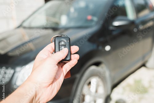Close-up of human caucasian hand using car key remote control. Car alarm