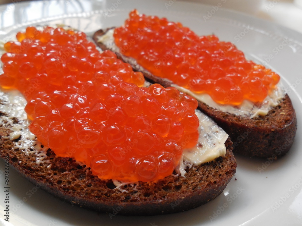 Delicious expensive delicacy red caviar on black bread with butter, on a plate. Delicious expensive delicacy red caviar on black bread with butter, on a plate.