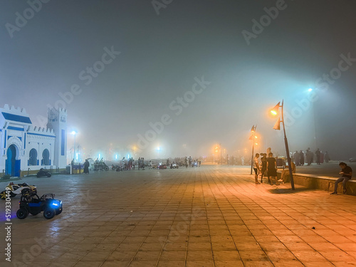  Crowd  of people walking in a public square on a foggy night photo