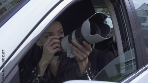 Young woman Paparazzi Photographer Capturing A Photo from car. Suspiciously Jealous wife Detective Spy Using A Big Professional Camera.