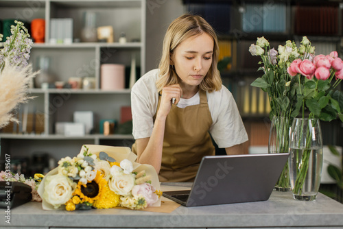 Florist woman using laptop. Greenhouse worker, female botanist close-up, small business owner. Gardener working in flower shop, plant store. photo