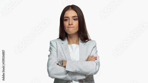 displeased businesswoman in grey blazer standing with crossed arms isolated on white.