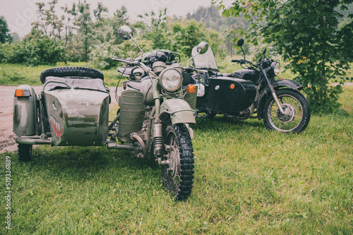 two old motorcycles with a sidecar in the countryside
