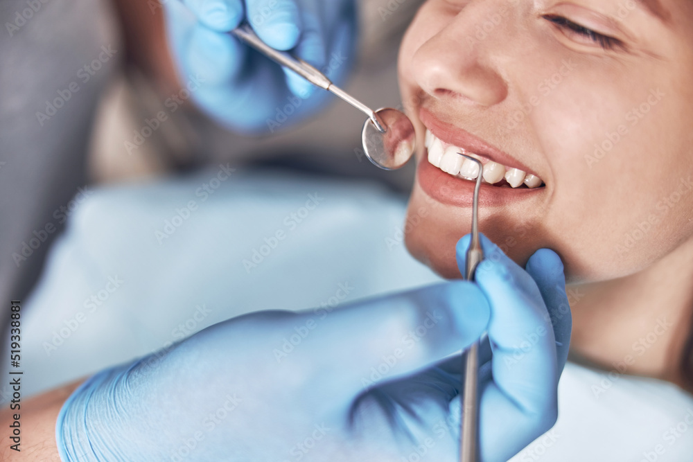 Confident mature doctor is checking teeth of young beautiful happy caucasian woman in modern clinic Confident mature doctor is checking teeth of young beautiful happy caucasian woman in modern clinic