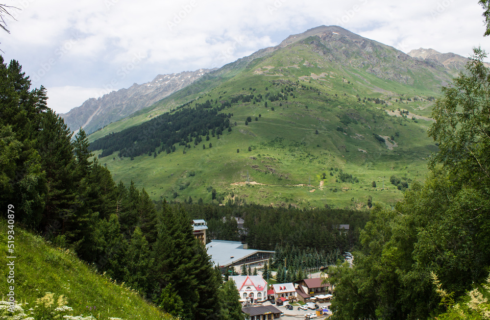 Panoramic view of the cheget glade among green hills and high mountains on a sunny summer day near elbrus russia Panoramic view of the cheget glade among green hills and high mountains on a sunny summer day near elbrus russia