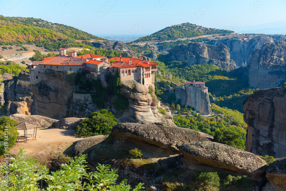 Beautiful scenic view, Orthodox Monastery of Varlaam, immense monolithic pillar, green foliage at the background of stone wall in Meteora, Pindos Mountains, Thessaly, Greece, Europe
