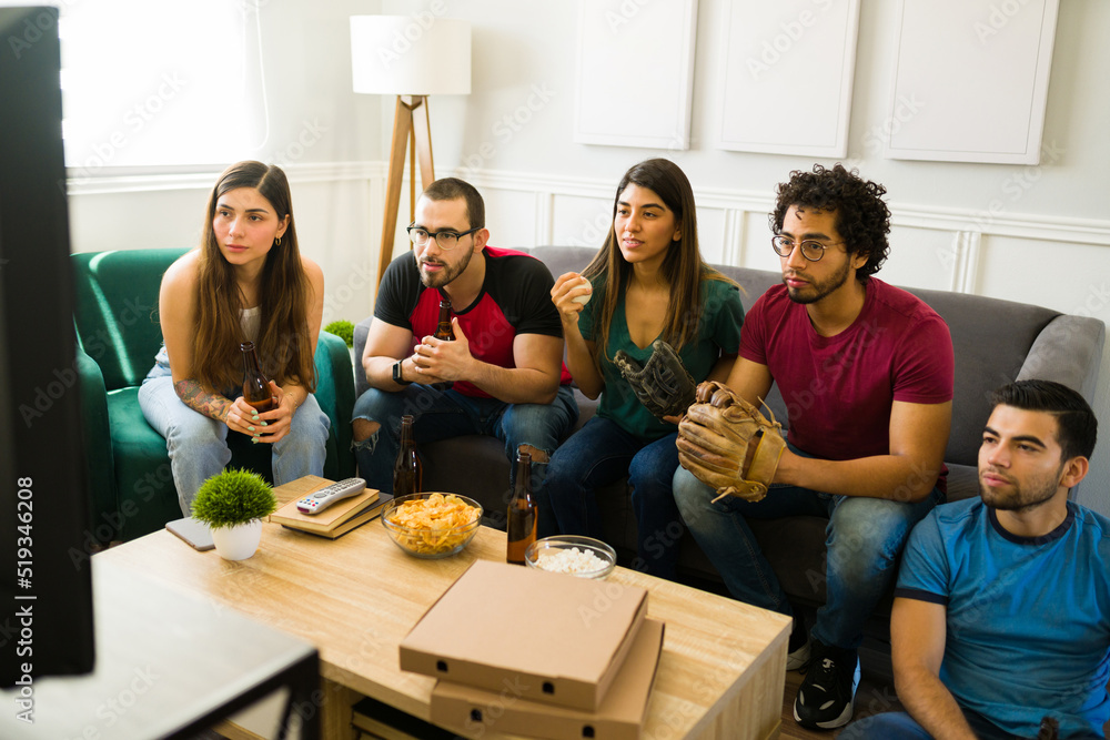 Friends looking tense while watching a baseball game on tv Friends looking tense while watching a baseball game on tv