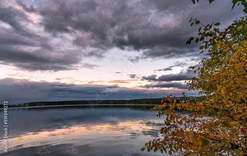 Fototapeta Naklejka Na Ścianę i Meble -  Sunset over a blue lake with green trees on the shore