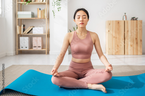 Asian female sitting on mat lotus pose do yoga exercise - Mindfullness and healthy lifestyle