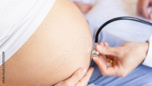 Pregnant patient doctor hospital. Medical clinic for pregnancy consultant. Doctor examining pregnancy woman belly holding stethoscope. Pregnancy, medicine health care concept.