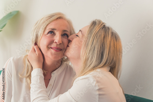 one woman kissing the other on a cheek closeup living room female couple. High quality photo