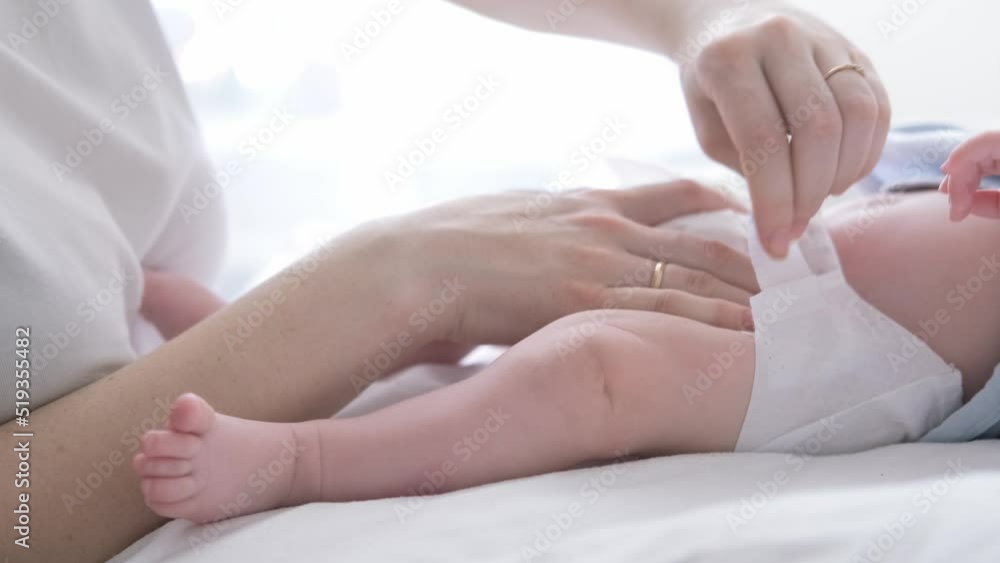 Mother changes diapers to her newborn baby, Little boy on changing table in clean dry nappy, Mom taking care of infant child, motherhood daily routine Mother changes diapers to her newborn baby, Little boy on changing table in clean dry nappy, Mom taking care of infant child, motherhood daily routine