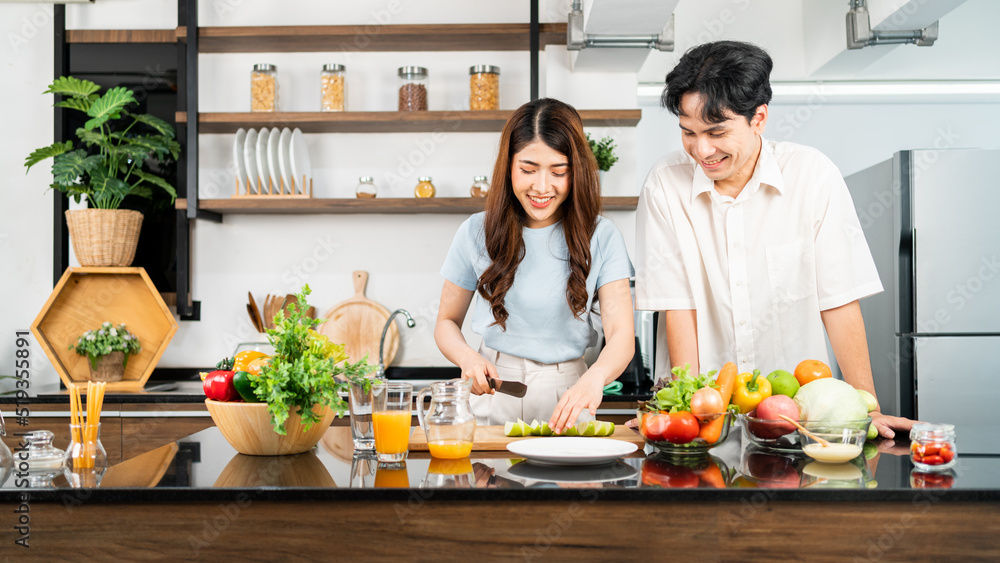 A happy couple prepares and cooks healthy salad with vegetables on a cutting board together in the home kitchen. Food cooking for young couple husband and wife in a good mood and healthy relationship. A happy couple prepares and cooks healthy salad with vegetables on a cutting board together in the home kitchen. Food cooking for young couple husband and wife in a good mood and healthy relationship.