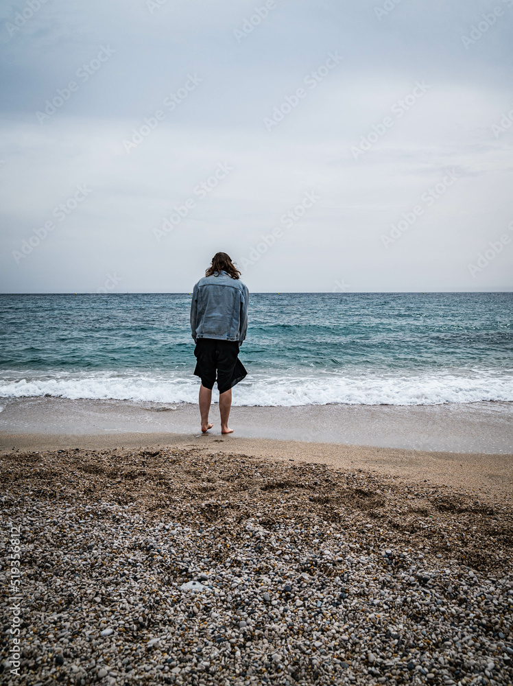 junge Frau steht vor Meer auf Strand