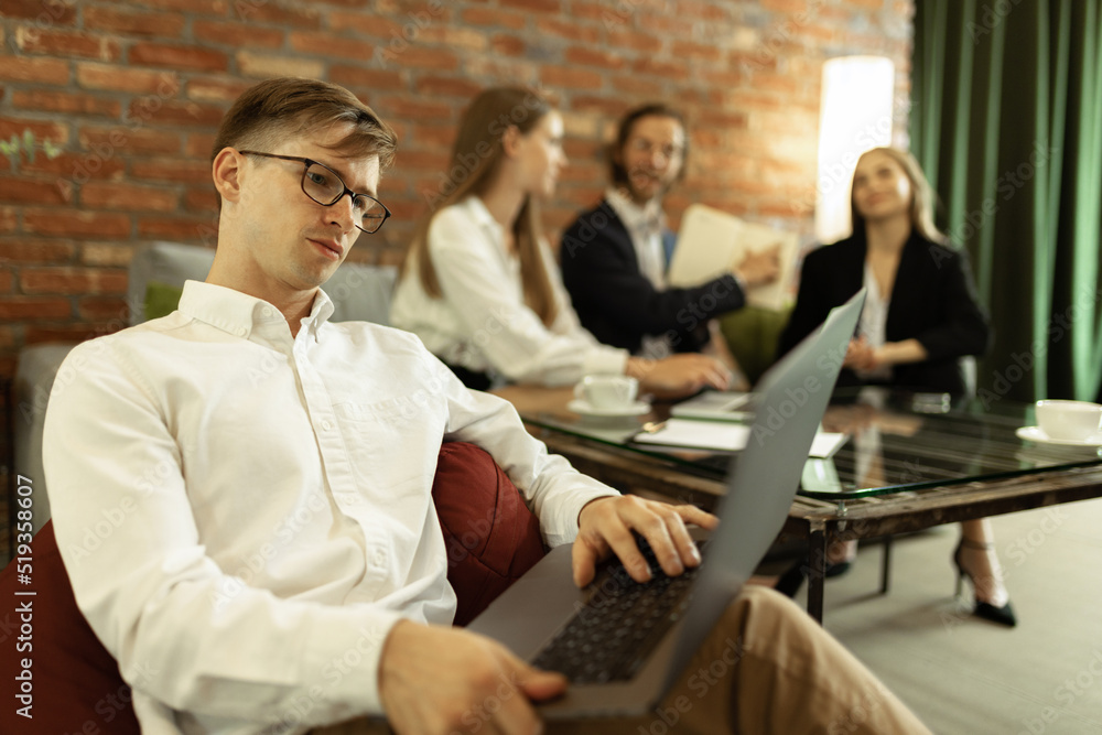 Portrait of concentrated young man, manager working on laptop at stylish office. Portrait of concentrated young man, manager working on laptop at stylish office.