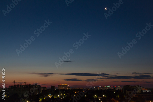 Photograph of the planet Venus and the Moon early in the morning in the predawn light over the city. Morning star and waning natural satellite of the Earth.