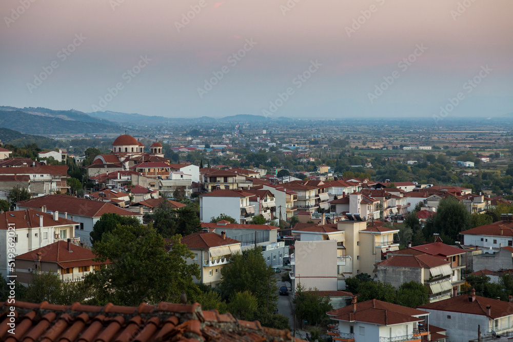 Churches and red roofs of white houses of the Greek city of Kalabaka at sunset, Meteora, Greece