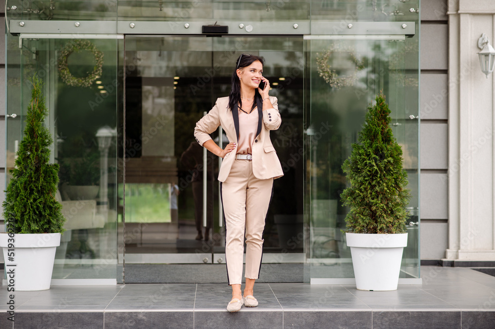 Fototapeta premium Successful business woman walking out the office building and have conversation on the phone
