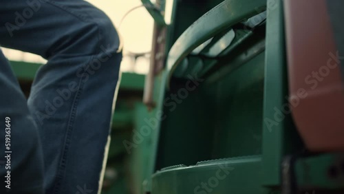 Man legs step tractor ladder sunrise closeup. Farmer go cabin before harvesting photo