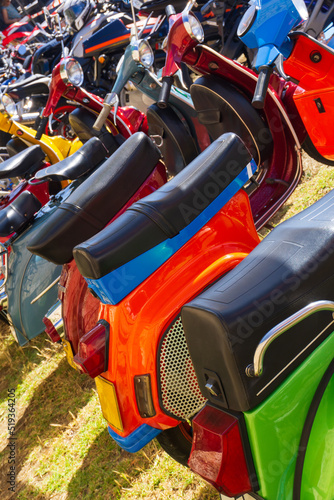 Row of brightly colored mopeds parked on the grass photo