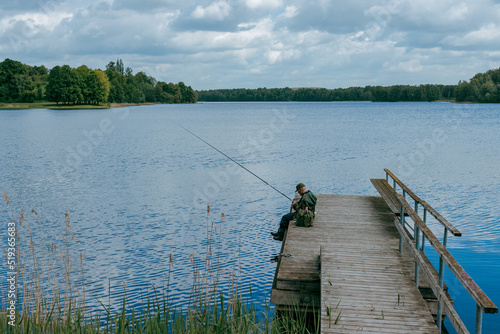 A man fishing on the lake sets alone