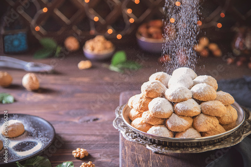 Arabic Cuisine; Delicious cookies for celebration of El-Fitr Islamic Feast( The Feast that comes after Ramadan). Sprinkling powdered sugar on Kahk (Eid Al-Fitr cookies).