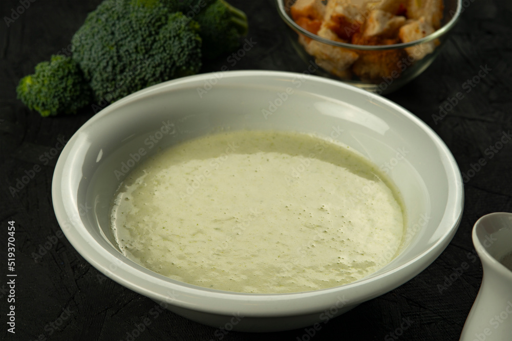 broccoli cream soup in white bowl on black desk broccoli cream soup in white bowl on black desk
