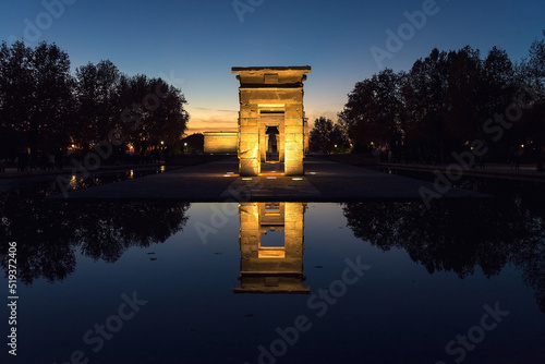 The Debod Temple illuminated at night reflected in the water.
