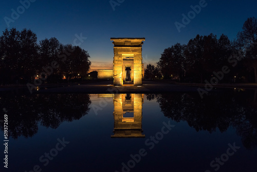 The Debod Temple illuminated at night reflected in the water.